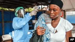 FILE - A woman has her temperature taken as part of Ebola prevention, prior to entering the Macauley government hospital in Freetown, Sierra Leone, Jan. 21, 2016. 