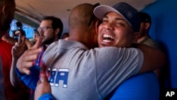 St. Louis Cardinals player Brayan Pena, from Cuba, embraces a former colleague before giving a baseball clinic to children in Havana, Cuba, Dec. 16, 2015.