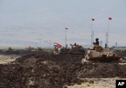 Turkish and Iraqi soldiers sit on Turkish tanks during the exercises in Silopi, near the Habur border gate with Iraq, southeastern Turkey, Sept. 26, 2017.