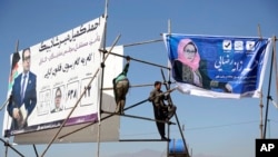Afghan men installs election posters of parliamentarian candidates during the elections campaign for the upcoming election in Kabul, Afghanistan, Oct. 9, 2018.