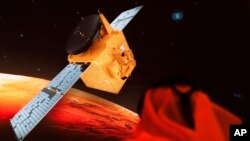 FILE An Emirati television journalist works on a script as a graphic showing the Emirates' Hope space probe to Mars flashes past him on a screen at the Mohammed bin Rashid Space Center in Dubai, United Arab Emirates, Sunday, July 19, 2020.