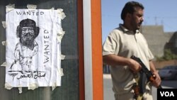 Tentara pemberontak berdiri di dekat poster 'Wanted: Moammar Gadhafi' di ibukota Tripoli, Libya (30/8).