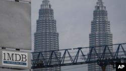 FILE - A 1MDB (1 Malaysia Development Berhad) logo is set against the Petronas Twin Towers at the flagship development site, Tun Razak Exchange in Kuala Lumpur, Malaysia.