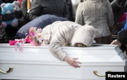 FILE - A woman reacts during a funeral of a victim of a shopping mall fire at a cemetery in Kemerovo, Russia, March 28, 2018.