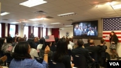 A hundred immigrants, from 31 countries, join in singing “America, the Beautiful” after becoming naturalized U.S. citizens. (M. Cuevas/VOA)