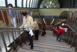 Government officials and volunteers disinfect as a precaution against the coronavirus at a subway station entrance in Goyang, South Korea, Aug. 25, 2020.