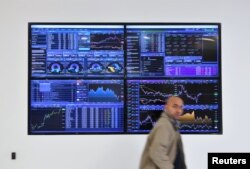 A man walks past a screen displaying share prices following a vote on Prime Minister Theresa May's Brexit 'plan B' at CMC Markets in London, Britain, Jan. 30, 2019.