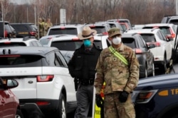 Police and U.S. Military personnel work amid a line of cars of people arriving for testing at a new drive-thru coronavirus disease (COVID-19) testing center in the Staten Island borough of New York City, New York, March 19, 2020.