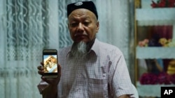 Ablikim Abliz holds up his phone with a photo of his uncle's family with an unknown Han Chinese man in Istanbul, Turkey, Aug. 22, 2018. He later heard that his uncle's front door was boarded up and sealed with police tape, and has not been able to contact him since.