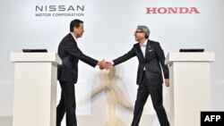 Makoto Uchida (kiri), Presiden dan CEO Nissan, bersalaman dengan Toshihiro Mibe, Presiden Honda, sebelum memberikan keterangan pers di Tokyo, Jepang, 1 Agustus 2024. (Foto: Richard A. Brooks/AFP) 