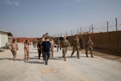 A handout picture released by the US Central Command on March 17, 2020, shows Qaim base commander US Major Luc Taylor, second from right, giving a tour of the base to the Iraqi Army aviation battalion.