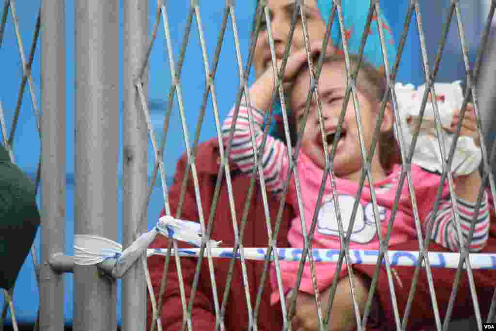 At a temporary refugee camp in Croatia, aid organizations are overwhelmed and unable to take care of all of the people. Families complain they have been separated from relatives as children are passed back and forth over a fence, Opatovac, Croatia, Sept. 22, 2015. (Heather Murdock/VOA)