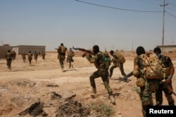 FILE - Asaib Ahl al-Haq Shi'ite militia fighters from the south of Iraq run during a mission to take control of Sulaiman Pek village from Islamist State militants, in the northwest of Tikrit city, Sept. 1, 2014.
