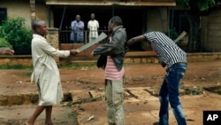 FILE - Muslim men organized in militias with machetes rough up a Christian man while checking him for weapons in the Miskine neighborhood of Bangui, Central African Republic, Dec. 13, 2013.
