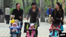 FILE - Women push babies in prams through a Beijing park during a public holiday, April 5, 2011.