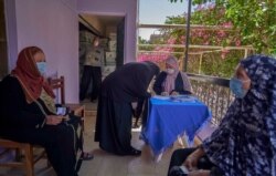 Mahrousa Mostafa, center, signs for food aid in Cairo, April 19, 2020. (Hamada Elrasam/VOA)