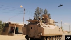 FILE - In this Tuesday, May 12, 2013 file photo, Egyptian Army soldiers patrol in an armored vehicle backed by a helicopter gunship during a sweep through villages in Sheikh Zuweyid, north Sinai, Egypt. An Egyptian militant group affiliated with the Islam