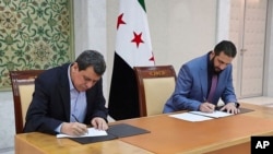 In this photo released by Syrian state news agency SANA, Syria's interim President Ahmad al-Sharaa, right, and Mazloum Abdi, the commander of the U.S.-backed Kurdish-led Syrian Democratic Forces, sign a deal in Damascus, Syria, March 10, 2025.