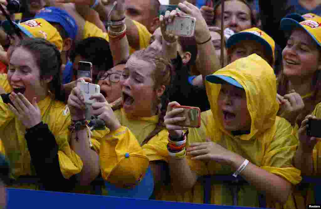 Pilgrims react as they take pictures of Pope Francis during the World Youth Days in Krakow, Poland.