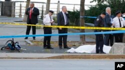 Authorities investigate the scene around a body covered under a white sheet next to a mangled bike along the bike path, Oct. 31, 2017, in New York. 