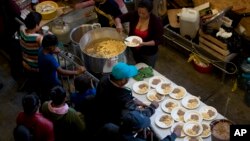 Breakfast of rice, beans and tortilla chips is prepared for Honduran migrants inside an empty warehouse that opened its doors to migrants in downtown Tijuana, Mexico, Dec. 18, 2018. The owner opened the warehouse, closed for years, so some migrants don't sleep outside.