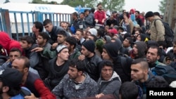 Migrants wait in front of a registration camp for migrants in Opatovac, Croatia, Sept. 22, 2015. 