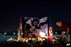FILE - A man lays flowers next to a photo of James Foley, the freelance journalist killed by the Islamic State group, during a memorial service in Irbil, Iraq, Aug. 24, 2014.