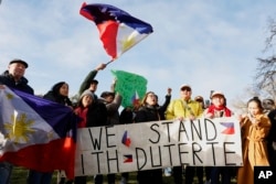 Supporters of former Philippine President Rodrigo Duterte wave a flag and banner during a demonstration outside the International Criminal Court detention center near The Hague in Scheveningen, Netherlands, on March 12, 2025.