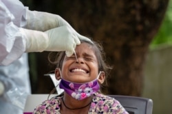 An Indian girl cries as a medical worker collects her swab sample for a COVID-19 test at a rural health center in Bagli, outskirts of Dharmsala, India, Sept. 7, 2020.