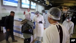 Afghan health workers wearing protective gear speak with passengers who arrived from China during a screening process for Coronavirus, at the Hamid Karzai International Airport in Kabul, Afghanistan, Monday, Feb. 3, 2020.
