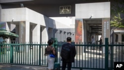 FILE - People stand at the gates of the Australian Embassy in Beijing, Sept. 1, 2020. 
