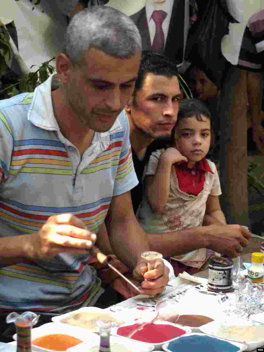 Emad Zaghlul Mustafa fills bottles with colored sand depicting landscapes. He says he moved into the tent village to protest the ouster of President Mohamed Morsi, but creates art to keep himself busy between rallies. (Heather Murdock for VOA)