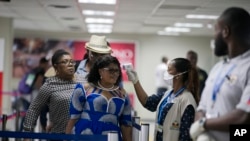 A Public Health Ministry nurse measures the temperature of a passenger arriving from France, at the Toussaint Louverture International Airport in Port-au-Prince, Haiti, Feb. 4, 2020.