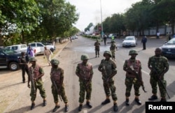 Nigerian army soldiers stand guard as they cordon off a road leading to the scene of a blast at a business district in Abuja, June 25, 2014.