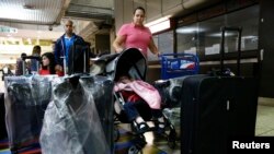 FILE - Natalie Pereira (C) queues to go through migration before her move to the U.S. with her family, after winning the Green Card lottery, at the Maiquetia airport in Caracas, April 8, 2014. 