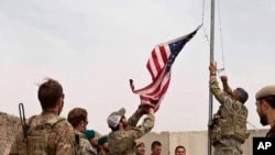 A U.S. flag is lowered as American and Afghan soldiers attend a handover ceremony from the U.S. Army to the Afghan National Army, at Camp Anthonic, in Helmand province, southern Afghanistan, May 2, 2021. (Afghan Ministry of Defense Press Office)