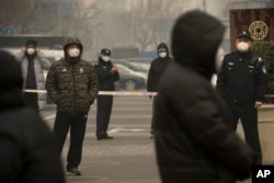 FILE - Plainclothes and uniformed police stand guard near Beijing's No. 2 People's Intermediate Court during a trial there of a human rights lawyer, in Beijing, China, Dec. 22, 2015.