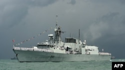 FILE - Crew members onboard the Royal Canadian Navy Halifax-class frigate, HMCS Ottawa wave along the strait near Changi Naval Base in Singapore, May 15, 2017. 