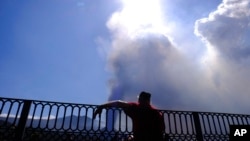 Un hombre mira hacia un volcán mientras continúa en erupción en la isla canaria de La Palma, España, el sábado 9 de octubre de 2021.