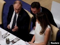 FILE - Russia's President Vladimir Putin talks to Melania Trump during the official dinner at the Elbphilharmonie Concert Hall during the G20 summit in Hamburg, Germany, July 7, 2017.
