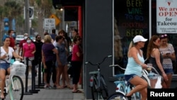 FILE - People stand in line at a restaurant by the beach after it was opened amid coronavirus disease (COVID-19) restrictions in Jacksonville, Florida, April 19, 2020.