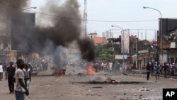 A man crosses a road near burning debris, during election protests in Kinshasa, Democratic Republic of Congo, Monday, Sept. 19, 2016.
