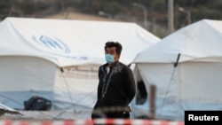 A man wearing a protective face mask walks at a new temporary camp for migrants and refugees, on the island of Lesbos, Greece, Sept. 19, 2020. 