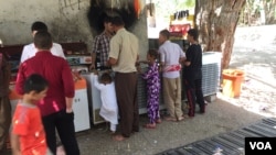 Yazidis are seen gathered outside the Lalish temple, enjoying shade, water and ice cream. Lalish, Iraq, July 31, 2015. (Photo - S. Behn/VOA)