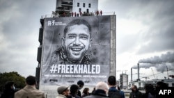 People attend the installation of a tarp depicting jailed Algerian journalist Khaled Drareni by French street artist and painter Christian Guemy, aka C215, in Paris, Oct. 15, 2020.