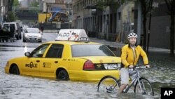 A bicyclist makes his way past a stranded taxi on a flooded New York City Street as Tropical Storm Irene passes through the city, August 28, 2011. A global warming-fueled sea level rise over the next century could flood millions in the US, according to a 