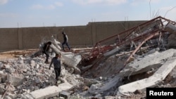 FILE - Youth inspect rubble of a damaged house after an airstrike yesterday on rebel-held Daraa al-Balad, Syria, April 7, 2017. 
