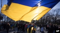 FILE - A woman waves a giant Ukrainian flag during a protest to mark two years since Russia's full-scale invasion on Ukraine, at the Brandenburg Gate, in Berlin, Saturday, Feb. 24, 2024. 