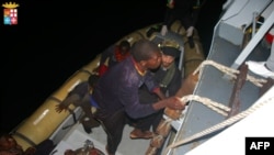 FILE - Refugees climbing aboard an Italian naval vessel near the Italian port of Pozzallo, south of Sicily. 