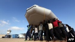 Des migrants secourus par les gardes-côtes libyens portent un canot gonflable sur la tête près de Tripoli, la capitale, 5 octobre 2015.